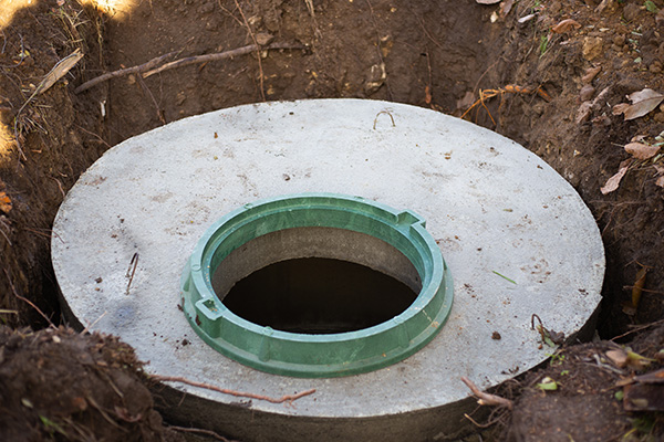 Construction of a septic tank. Large concrete rings embedded in the ground, from above an open sewer hatch, unprotected by a cover from falling.