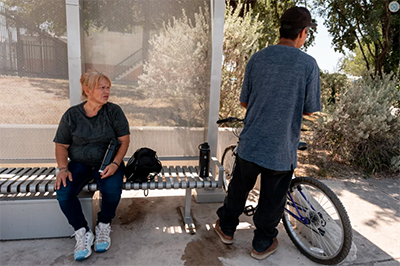 two people talking at a bus stop.